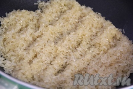 В глубокую сковороду влить масло и всыпать рис. Обжарить рис на масле, периодически помешивая. Масло должно полностью впитаться в рис.