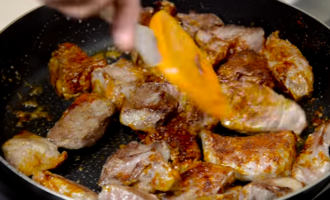 Посыпьте обжаренное мясо сухой паприкой и еще немного пожарьте.