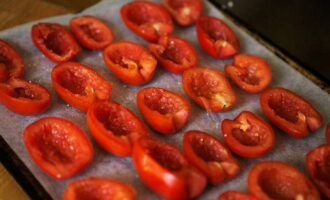 На противне разложить половинки томатов срезом вверх плотно друг к другу. Присыпать овощи солью, сахаром и свежемолотым перцем.