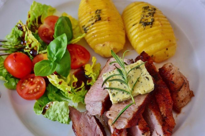 свиной стейк порезанный с салатом и картофелем